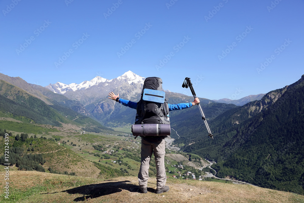 Obraz premium tourist with a large backpack and raised hands standing in front of the mountains.