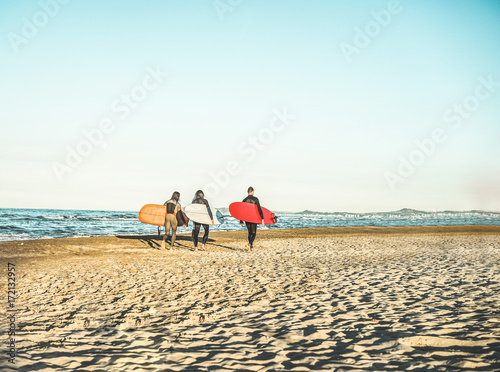 Surfer friends walking on the beach holding surf boards - Extreme sport concept