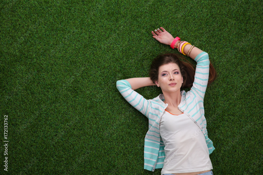 Beautiful redhead women lying down on green grass in summer time in the park