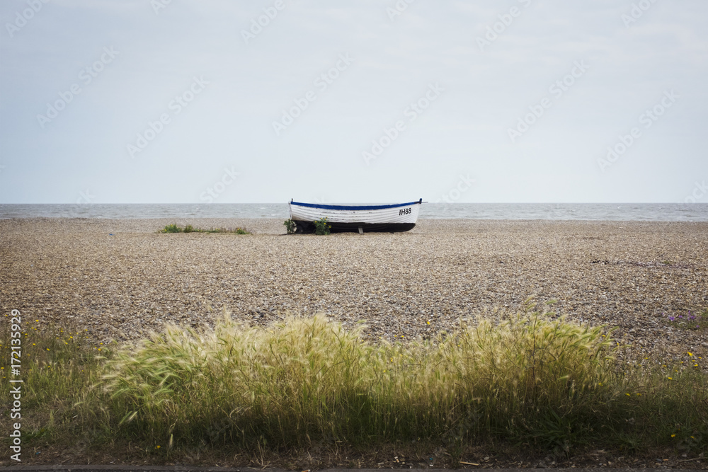 Small wooden fishing boat on a shingle beach Small wooden fishing boat on a shingle beach