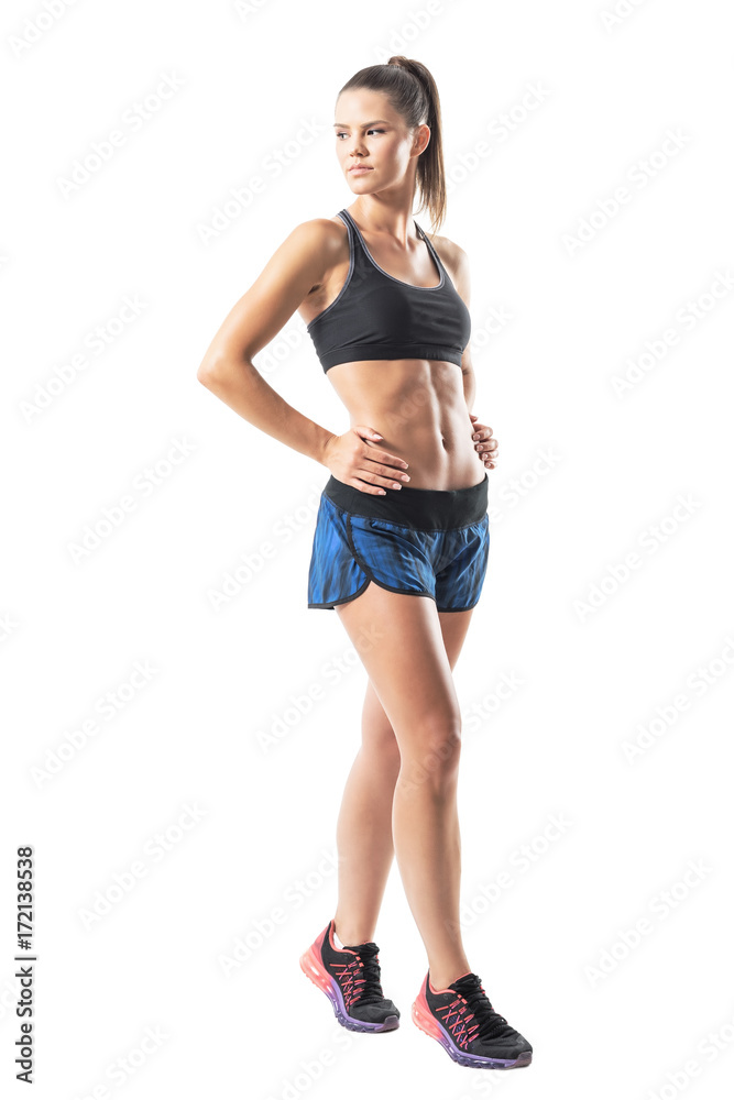Side view of confident tough athletic woman posing and looking back over shoulder. Full body length portrait isolated on white studio background. Side view of confident tough athletic woman posing and looking back over shoulder. Full body length portrait isolated on white studio background.