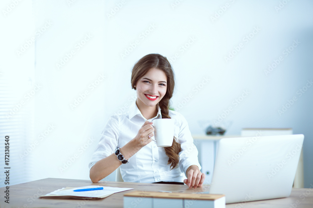 Young businesswoman sitting on the desk with with cup Young businesswoman sitting on the desk with with cup