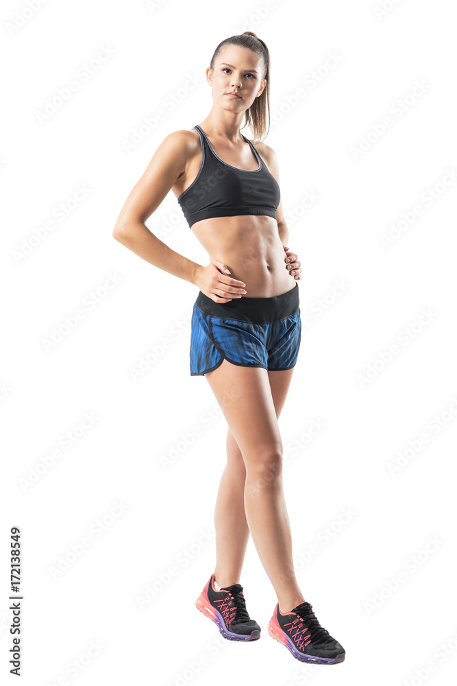 Gorgeous confident athletic fitness woman with perfect abs posing with hands on hips. Full body length portrait isolated on white studio background. Stock Adobe Stock