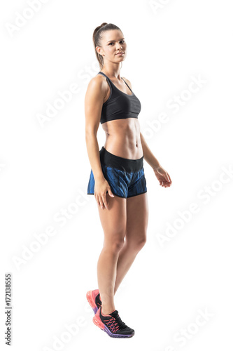 Side view of relaxed young fitness woman walking and looking at camera. Full body length portrait isolated on white studio background.  © sharplaninac