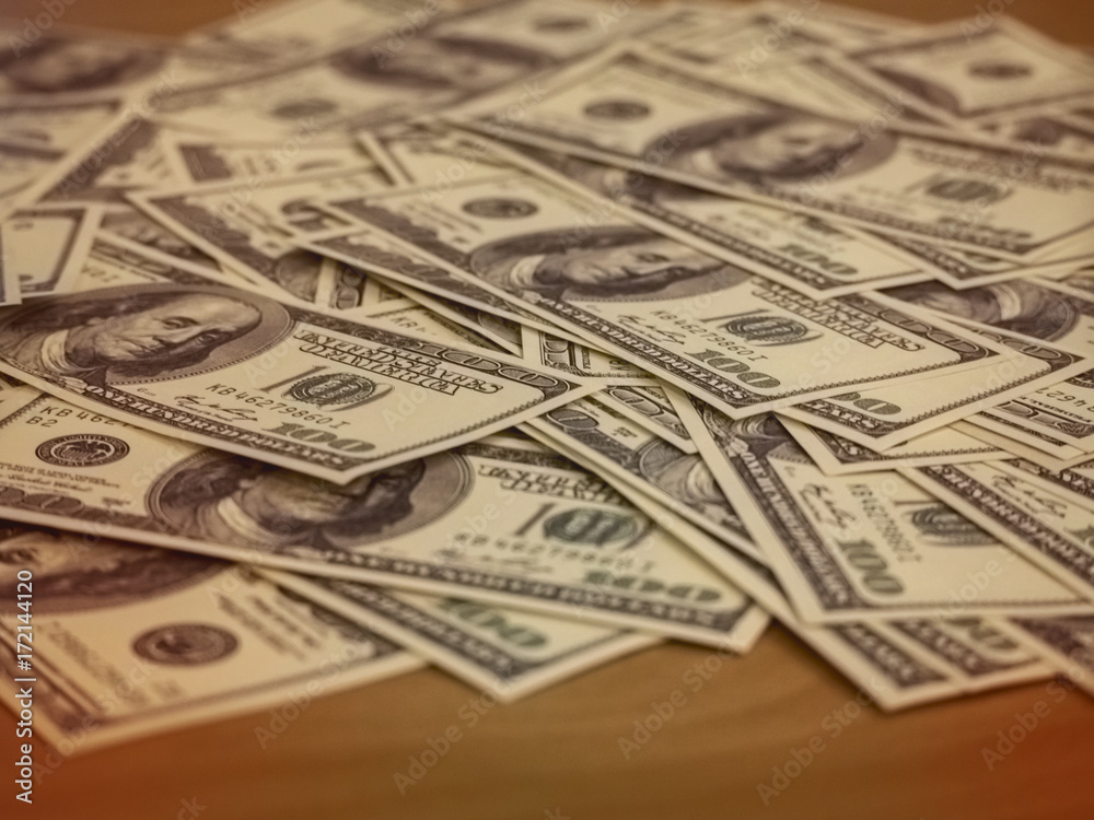 The blurred US Dollars money plenty on wooden desk,abstract art design,vintage tone.blurry light background.