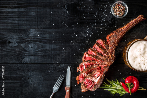 Photos Barbecue dry aged rib of beef with spice, vegetables and a glass of light beer c