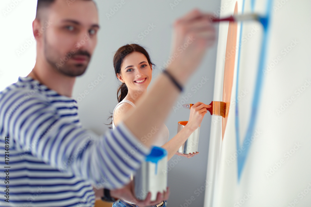 Portrait of happy smiling young couple painting interior wall of new house. young couple