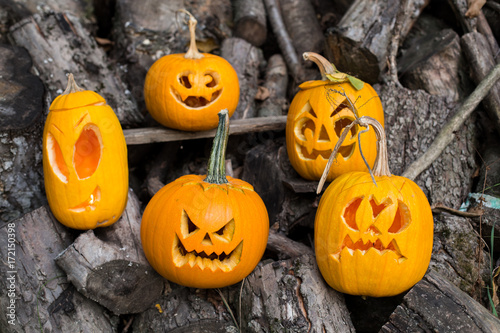 Halloween themes. Composition of five carved halloween pumpkins on wooden background. Pumpkins with different halloween faces. photo