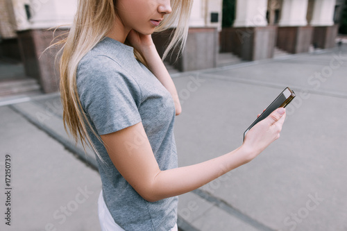 Modern communication in real life. Girl with gadget, young blonde with mobile phone on street © Photodrive