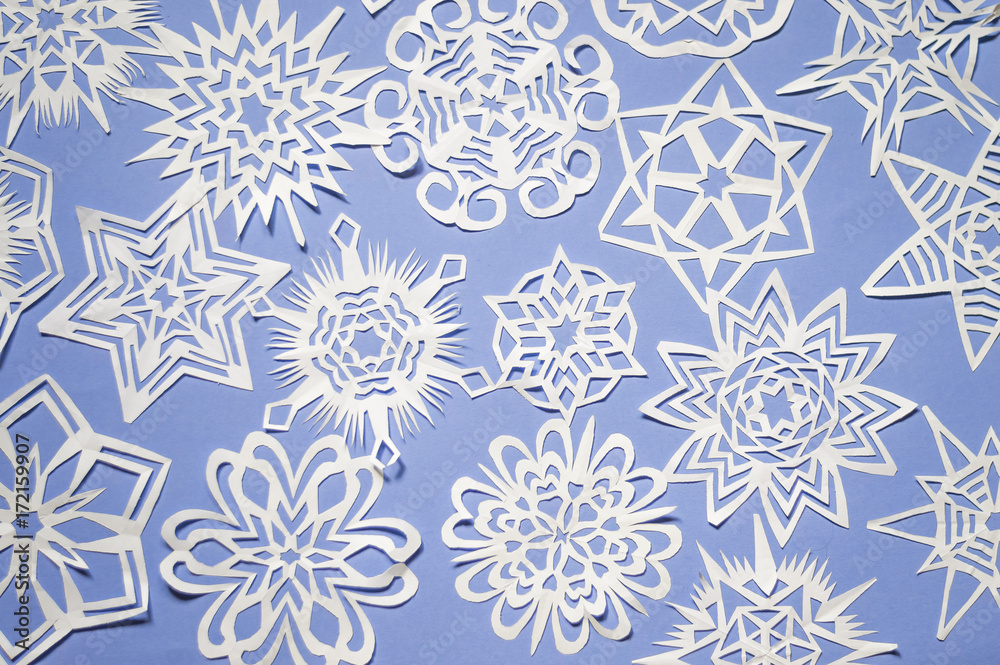 snowflakes cut from paper on blue background Christmas texture or background