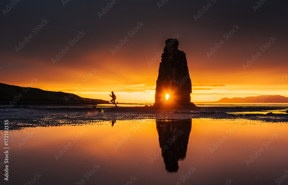 Is a spectacular rock in the sea on the Northern coast of Iceland. On this photo Hvitserkur reflects in the sea water after the midnight sunset - obrazy, fototapety, plakaty 