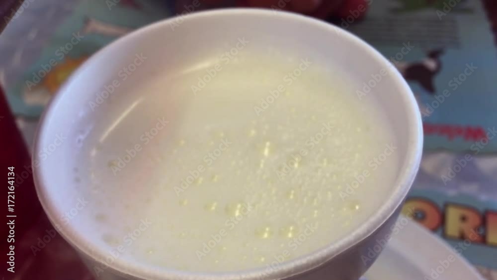 Traditional authentic Cuban cafe con leche coffee brew being poured in slow motion over foamy white milk in a styrofoam cup Traditional authentic Cuban cafe con leche coffee brew being poured in slow motion over foamy white milk in a styrofoam cup