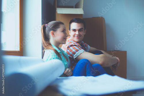 Couple moving in house sitting on the floor. Couple