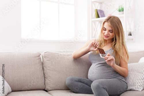 Young pregnant woman eating chocolate bar