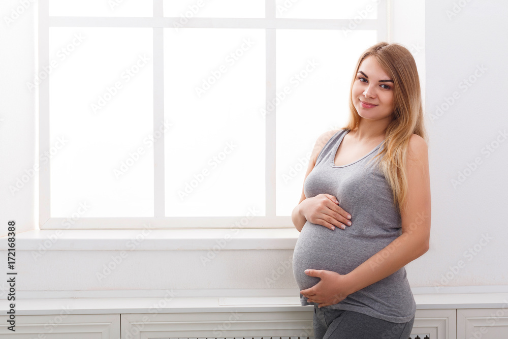 Smiling pregnant woman dreaming about child, copy space.