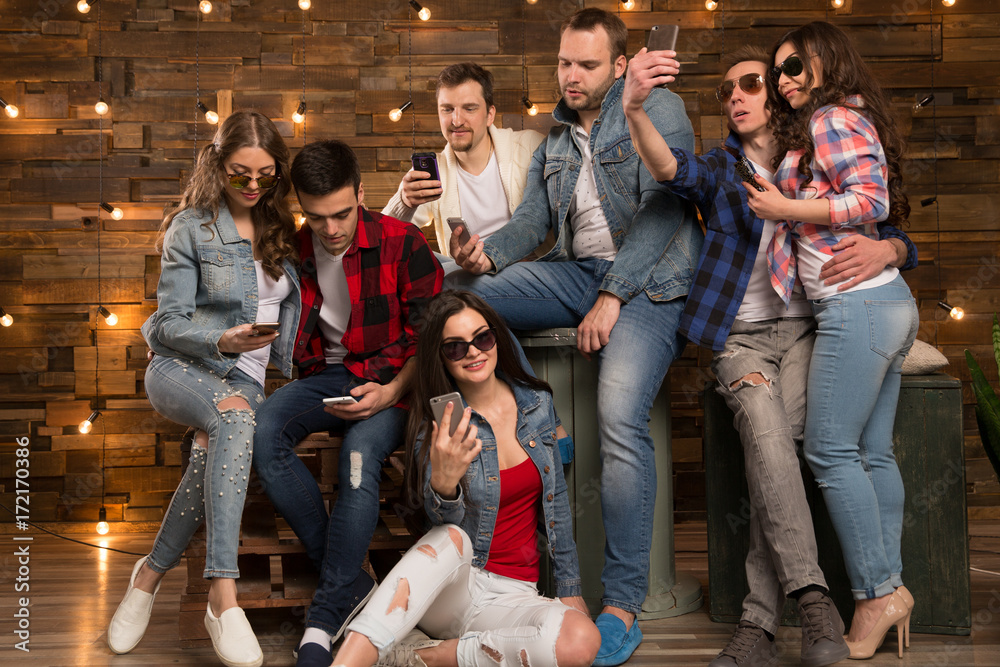 Group of  friends happy people, students with smartphones in their hands are watching social networks. Having fun on the Internet online. Positive girls and boys Friendship between men and women.