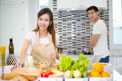 Asian couple cooking for food and salad for romantic diner in kitchen room in the home.