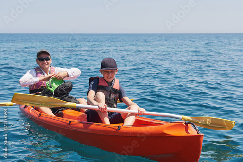 Boat kayaking near cliffs on a sunny day. Kayaking in a quiet bay. Amazing views. Travel, sports concept. Lifestyle. A happy family. © standret