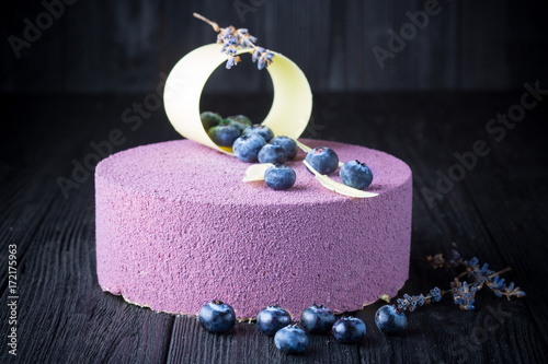 Delicious lavender cake with blueberries on black wooden table