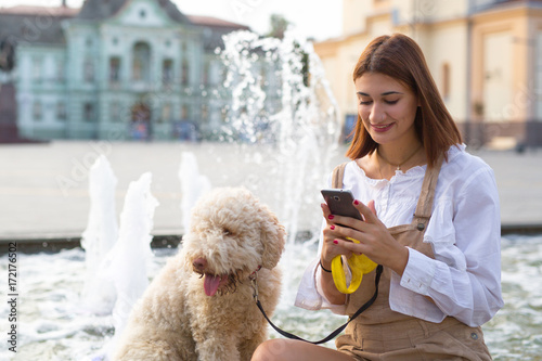 Woman using smart phone and enjoying summer days with her dog.