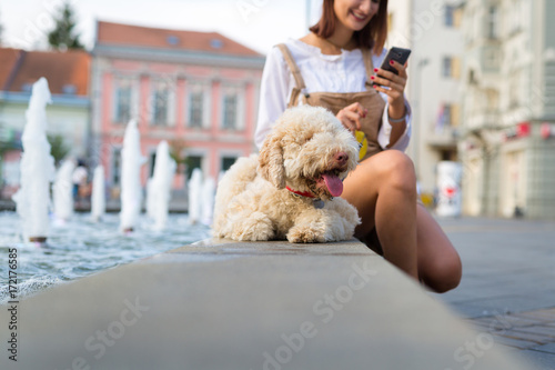 Woman using smart phone and enjoying summer days with her dog.