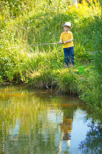 Little boy is engaged in fishing in a pond. Child with a dairy in his hands. © Miramiska