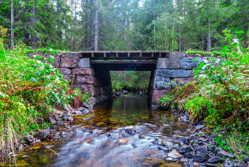 Small river flowing through a bridge in the forest