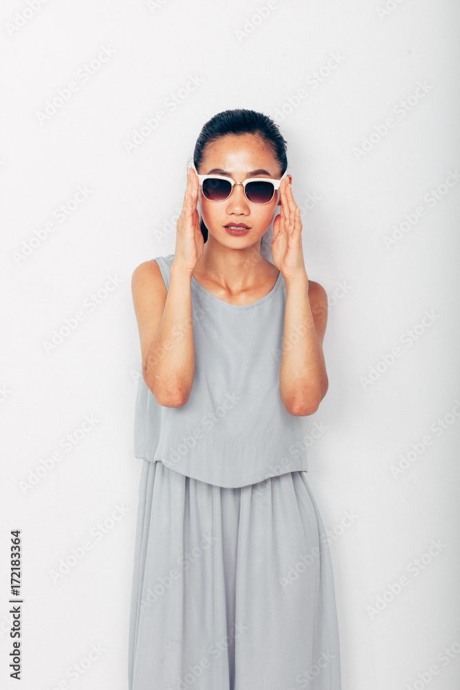 Young beautiful Asian woman in summer grey clothes and sunglasses