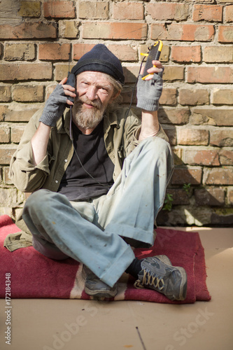 Portrait on tramp using solar energy battery. Old man liviing in the streets using modern technologies. photo