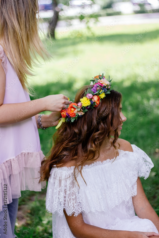 Naklejka premium Putting a flower wreath to the hairs of young beautiful model.