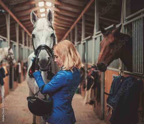 Middle-aged woman with her horse in a stall