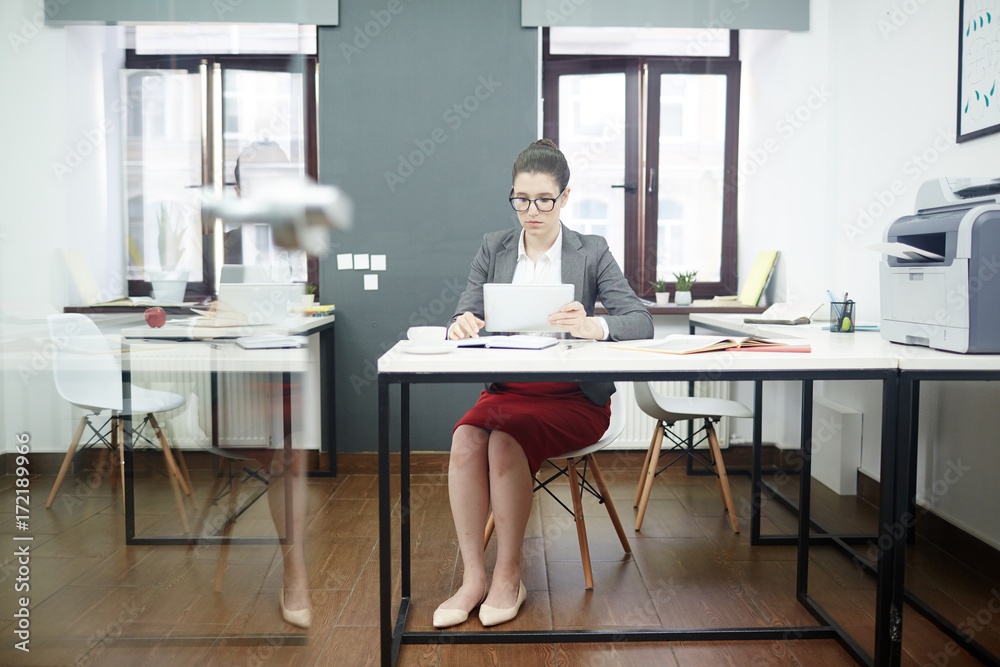 Young specialist with tablet looking through online sales rate Young specialist with tablet looking through online sales rate