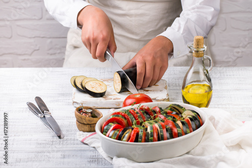 Young female chef prepares ratatouille. Cooking traditional french dish - ratatouille.