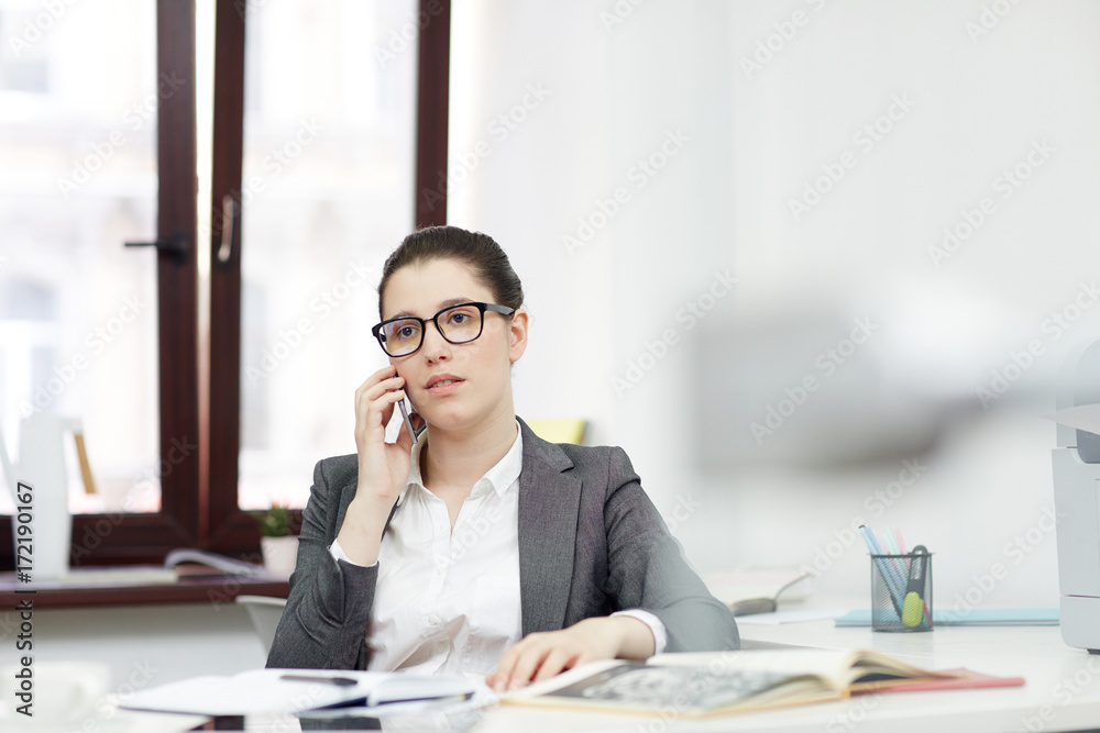 Young secretary or office manager speaking on the phone during working day Young secretary or office manager speaking on the phone during working day