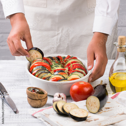 Young female chef prepares ratatouille. Cooking traditional french dish - ratatouille.