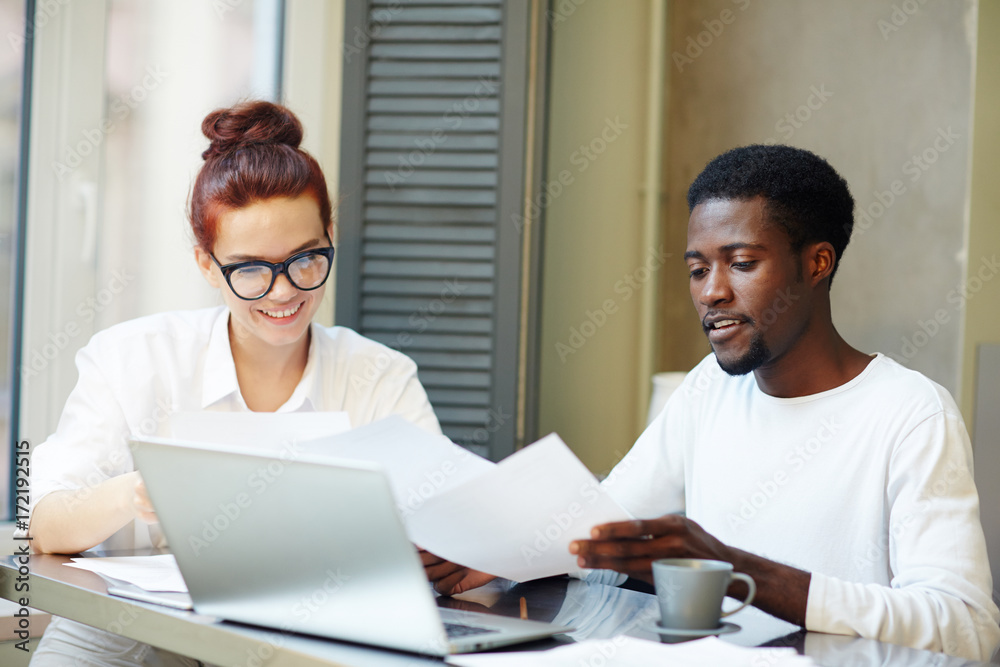 Young man and woman looking through financial papers while working at home office Young man and woman looking through financial papers while working at home office