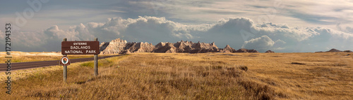 Wide landscape panoramic of badlands national park with signage entering into storm clouds