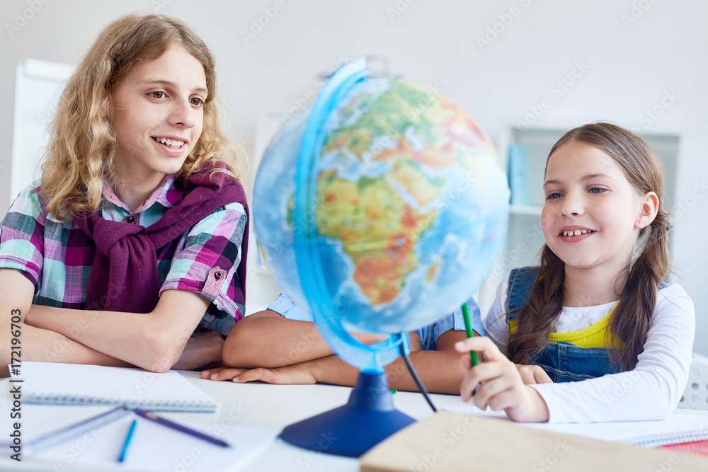 Two classmates looking at globe model and discussing lands Two classmates looking at globe model and discussing lands