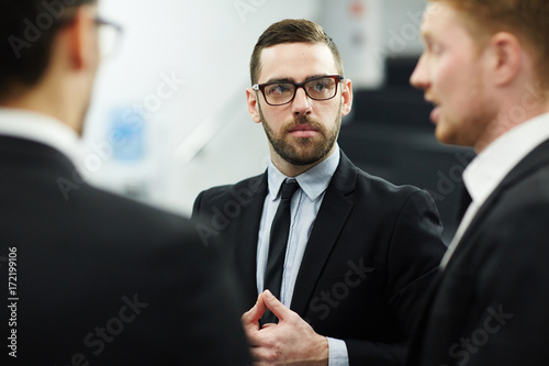 Team of modern business partners in suits having discussion at meeting