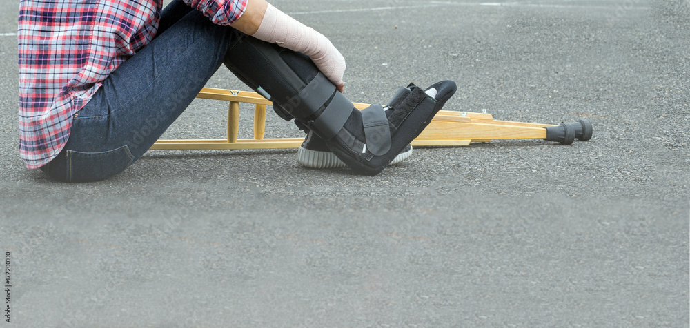 broken leg, injury woman wearing shirt and jeans with arm splint, black leg  cast, wooden crutches and sitting on floor Stock-Foto | Adobe Stock