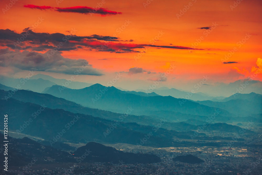 High angle aerial view over Pokhara City, Nepal at evening. Blue mountain misty range and orange sunset cloudy sky in the background. Nature landscape. Travel, holidays, recreation concept