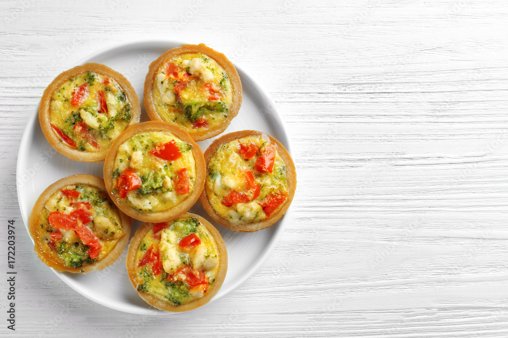 Plate with broccoli quiche tartlets on table Plate with broccoli quiche tartlets on table
