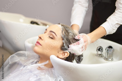 Lady getting her head washed. Young female in beauty salon. Professional hair care products.