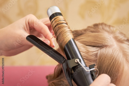 Blonde hair and curling iron. Hair styling tool, close up. Buy curling iron online.