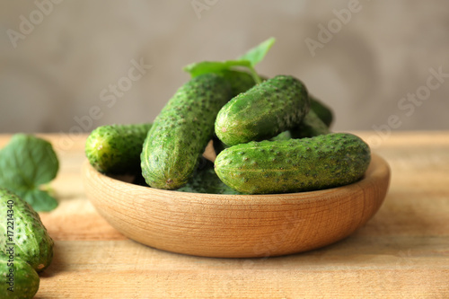 Green fresh cucumbers in bowl on wooden table