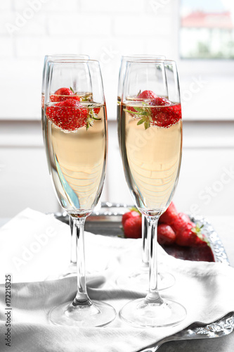 Glasses of delicious wine with strawberry on table