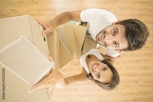 The man and woman hold a boxes and look to the camera. view from above