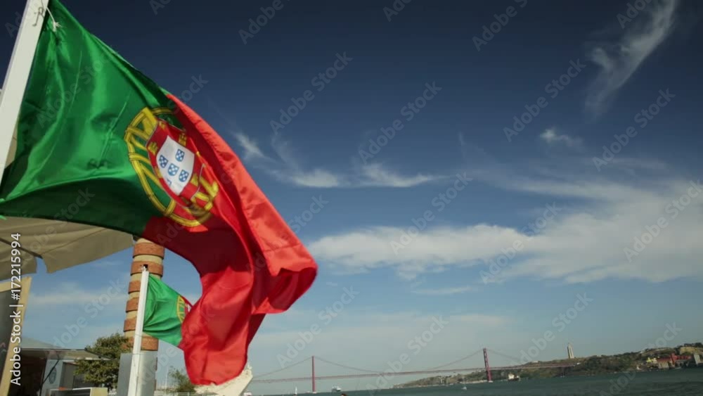 Symbols and icons in Lisbon city: Belem Lighthouse, flags of Portugal waving, Discoveries Monument, Bridge of 25 April and Tagus river. Belem District, Lisbon, Portugal, Europe.