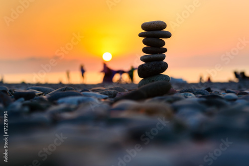 Stones pyramid on sand symbolizing zen, harmony, balance. Black sea at sunset in the background. photo