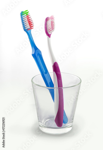 Blue and pink toothbrushes in a glass
